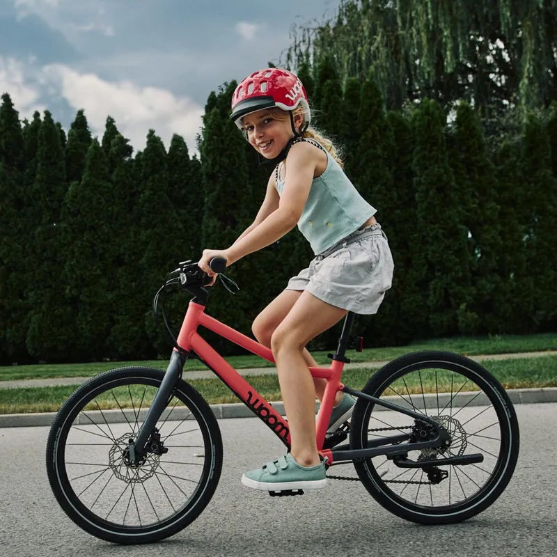 Girl in a woom helmet riding a red woom bike